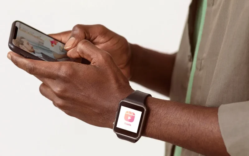 Individual holding a smartphone in one hand while wearing a smartwatch on the other wrist.
